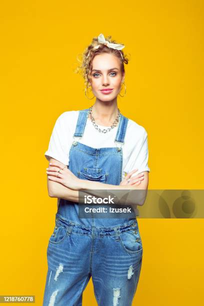Portrait Of Confident Young Woman In Coveralls On Yellow Background Stock Photo - Download Image Now