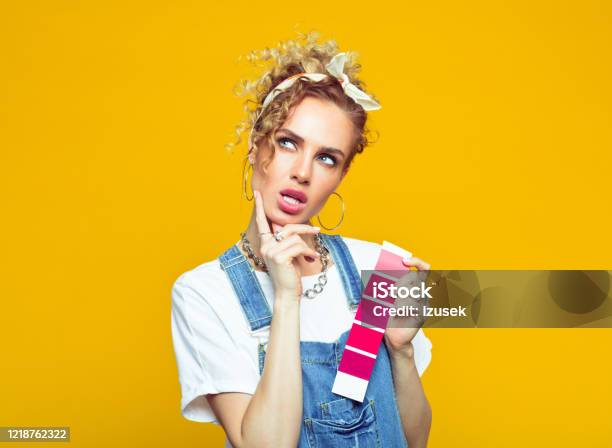 Young Woman In Coveralls Holding Color Swatch Stock Photo - Download Image Now - Choosing, Home Improvement, Jeans