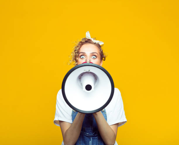 istock Young woman in dungarees shouting into megaphone 1218762621