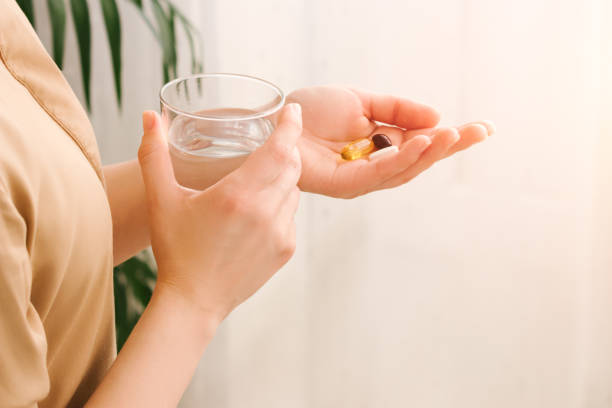 woman holding pills and a glass of water. - eating female healthcare and medicine healthy lifestyle imagens e fotografias de stock