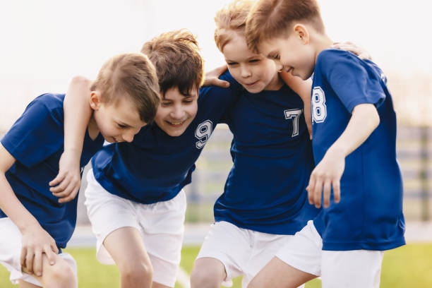 jugadores del equipo de fútbol infantil. happy sports boys en un equipo escolar. niños acurrucados en un equipo en la competición de torneos. jugadores reunidos en un círculo. niños en ropa deportiva de fútbol - soccer child coach childhood fotografías e imágenes de stock