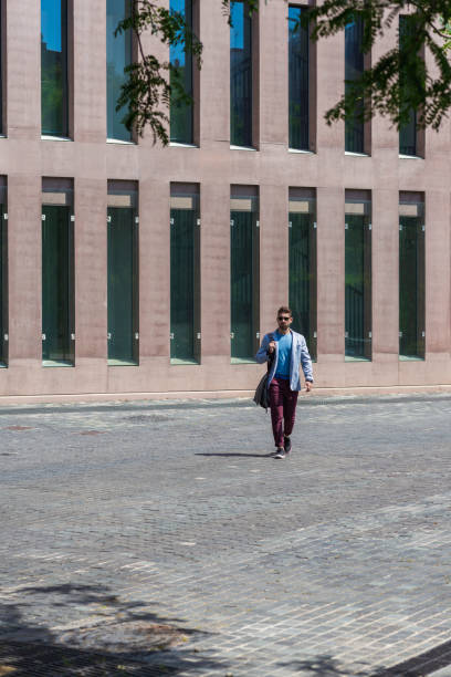 istock Portrait of a trendy young man walking while holding a shoulder bag 1218770834