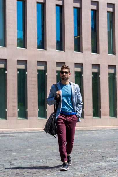 istock Portrait of a trendy young man walking while holding a shoulder bag 1218770840
