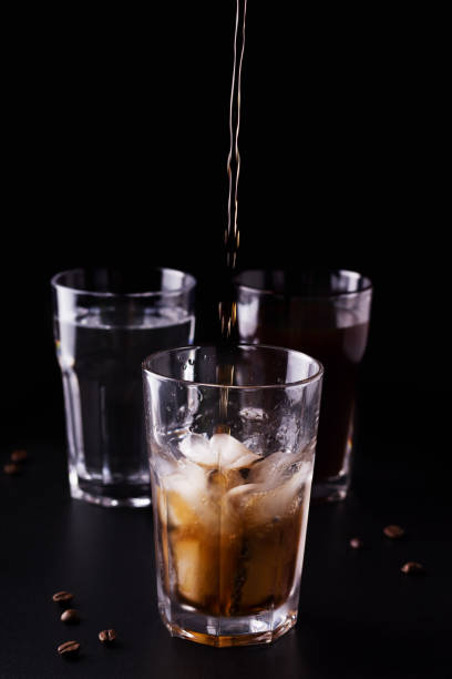 istock coffee is poured into a glass with ice. refreshing drink on a black background 1218771884