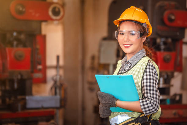 Asian female worker holding clipboard with  blurred factory background stock photo