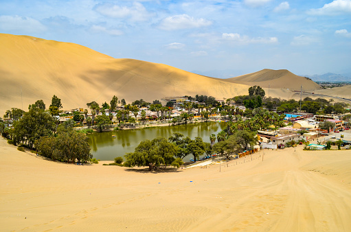Huacachina is a desert oasis and tiny village just west of the city of Ica in southwestern Peru. At its center are the green waters of the Huacachina Lagoon, ringed by palm trees and thought to have therapeutic properties. The lagoon's shores are dotted with bars and clubs. Dune buggies run across the high, rolling sand dunes surrounding the village.