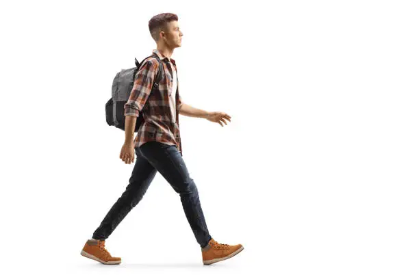 Full length profile shot of a male student with a backpack walking isolated on white background