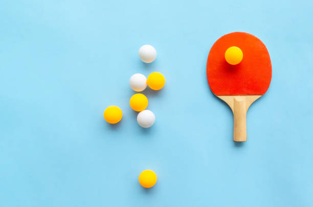 racchetta rossa per ping pong con palline bianche gialle su sfondo blu. attrezzatura sportiva da ping pong in stile minimale. lay piatto, vista dall'alto, spazio di copia - table tennis table tennis racket racket sport ball foto e immagini stock