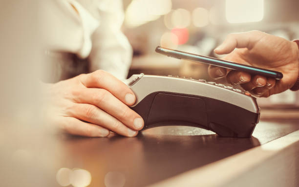 istock Customer hand pays with smartphone in store using NFC technology. Mobile phone paying the bill with contact less technology. 1218777112