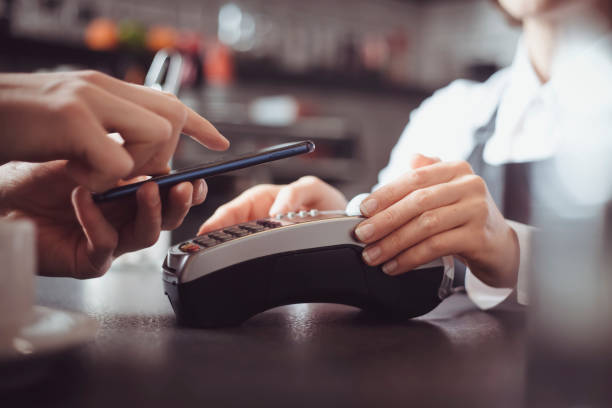 istock Customer hand pays with smartphone in store using NFC technology. Mobile phone paying the bill with contact less technology. 1218777261
