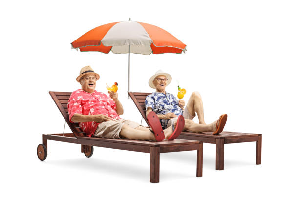 傘を持ってサンベッドに横たわっているカクテルを持つ2人のシニア男性観光客 - umbrella two objects cocktail drink ストックフォトと画像