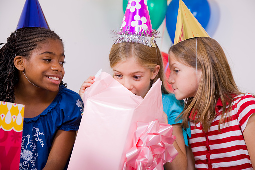 A group of girls opening presents at a birthday party.