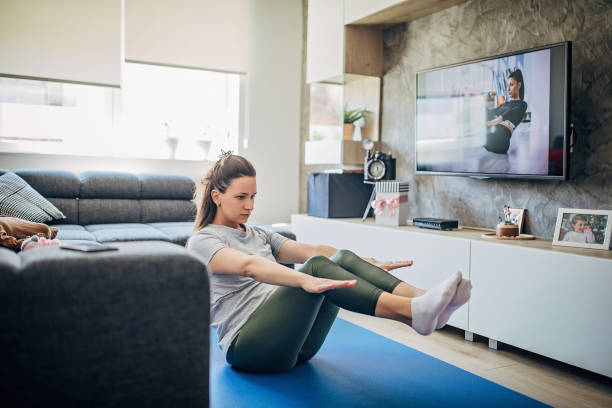 istock Mother exercising in front of TV while her baby son is lying on sofa 1218778757