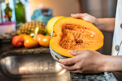 Woman holding half a pumpkin in the domestic kitchen