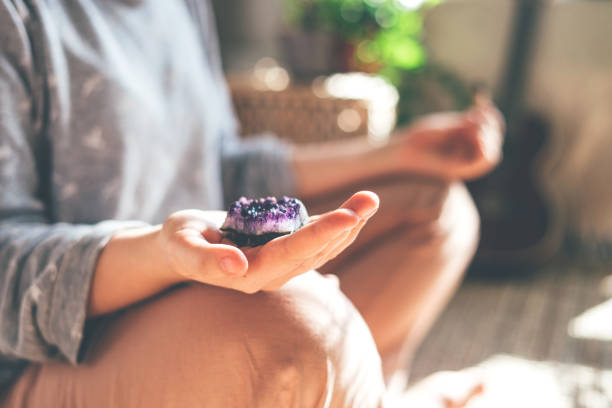 joven hermosa mujer está meditando con un cristal en la mano. - amatista fotografías e imágenes de stock