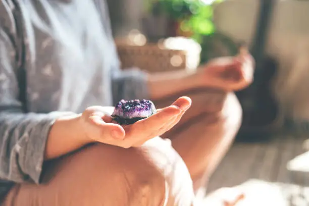 Photo of Young beautiful woman is meditating with a crystal in her hand.