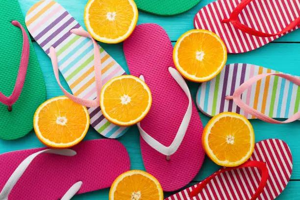 Photo of Summer fun time and flip flops. Slippers and orange fruit on blue wooden background. Mock up and picturesque. Top view. Sandals