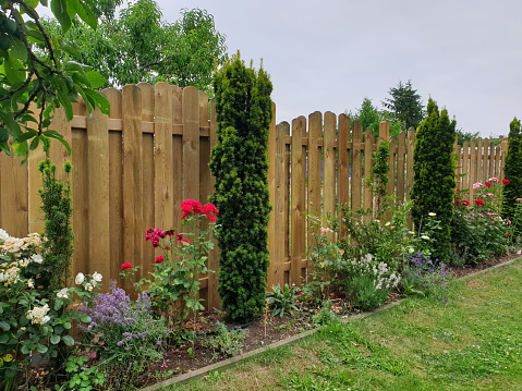 Garden fence made of wood as a visual protection with a flower bed