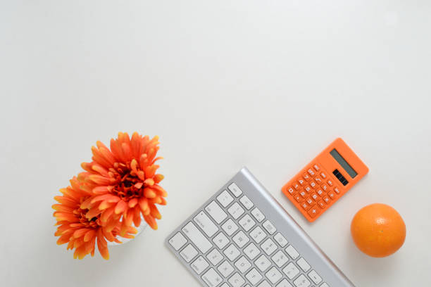 istock Creative work space background with keyboard, calculator, orange and flower decoration 1218787823