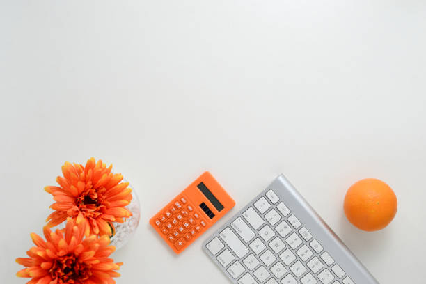 istock Creative work space background with keyboard, calculator, orange and flower decoration 1218787824