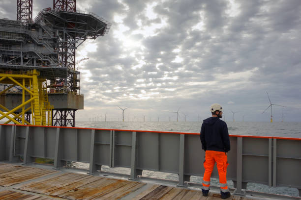 istock Technician standing on transfer vessel deck and in the morning and looking on offshore wind farm and offshore platform around 1218789529