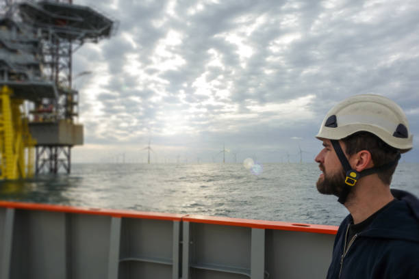 istock Technician standing on transfer vessel deck and looking on offshore platform in the morning and offshore wind farm is around 1218789538
