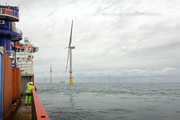 Technician standing on transfer vessel deck in the morning and looking on offshore wind farm and offshore platform around Technician standing on transfer vessel deck and in the morning and looking on offshore wind farm and offshore platform around offshore wind farm stock pictures, royalty-free photos & images