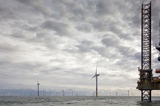View on offshore wind-farm with 8MW wind-turbines and offshore platform in German north Sea with dramatic clouds