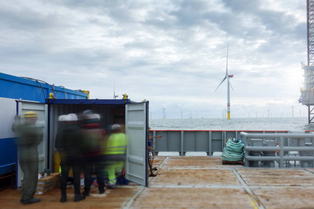 istock Group of Technicians standing on transfer vessel deck and preparing equipment for offshore project in the morning and offshore wind farm and offshore platform is behind 1218789708