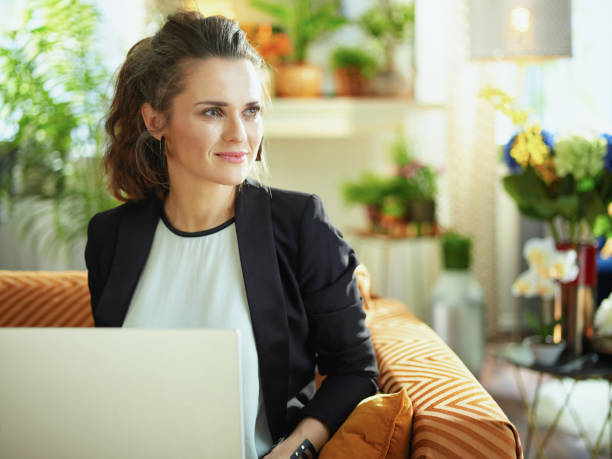 istock pensive trendy woman using website while sitting on couch 1218791023