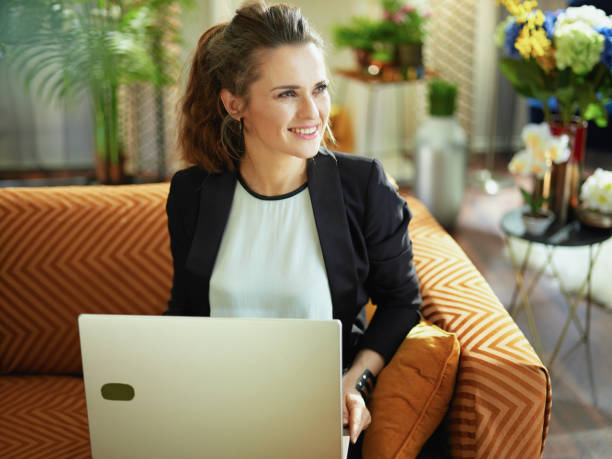 istock happy stylish woman typing message while sitting on divan 1218791090
