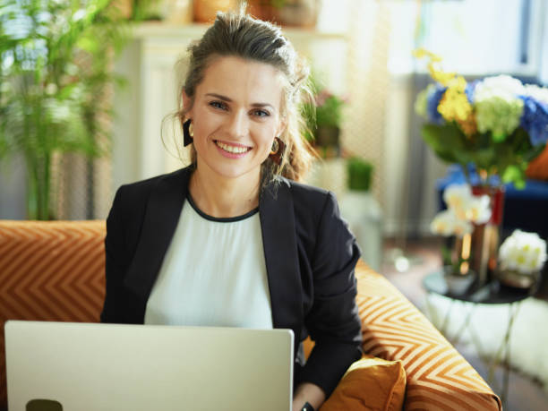 istock happy housewife writing on laptop while sitting on divan 1218791165