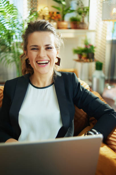 istock smiling woman writing on laptop while sitting on couch 1218791193