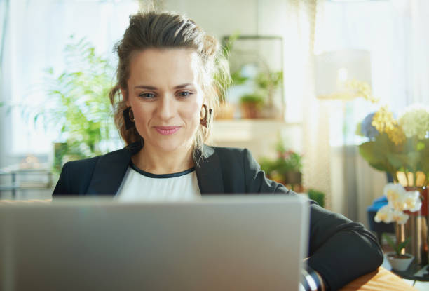 istock elegant housewife surfing web on laptop while sitting on couch 1218791269