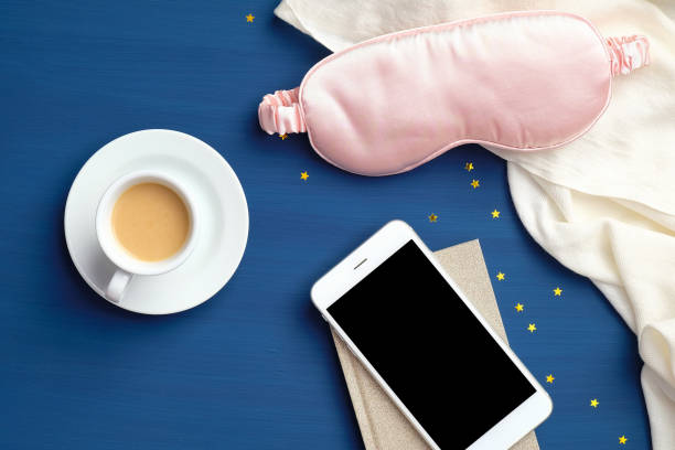 istock Sleeping app for insomnia, fall asleep concept. Flat lay home desk with cup of coffee, sleep mask, blanket and smartphone with blank screen mockup 1218791572
