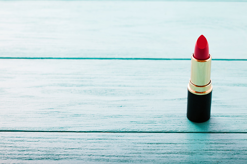 Pink lipstick on blue wooden background. Copy space. MAke up product and cosmetic concept. Selective focus