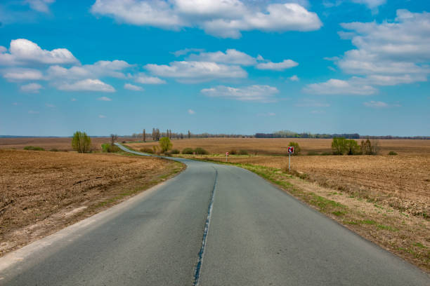 istock Deserted road. Clear blue sky with white clouds. Winding road 1218794480