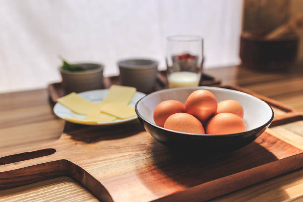 Omelet ingredients on a wooden table and cutting board.
