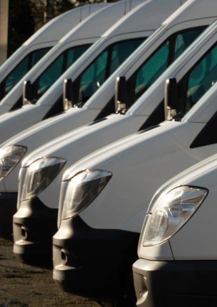 kommerzielle lieferwagen, in einer reihe geparkt. - van white truck mini van stock-fotos und bilder