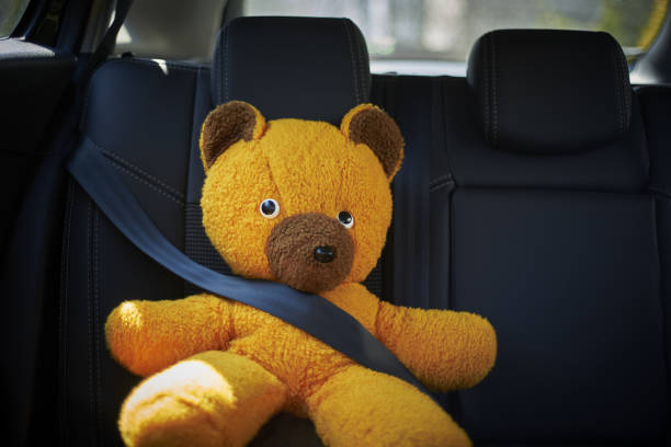 istock Teddy Bear Sitting On Car Seat With Belt Buckled 1218803953
