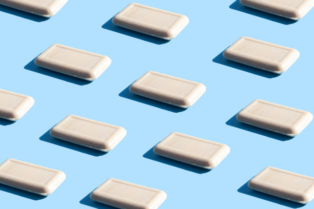 istock Pattern of pieces of solid soap on a blue background with trendy sunlight. Wash your hands. Soap against bacteria and viruses. Compliance with hygiene and sterility to combat coronavirus. 1218804170