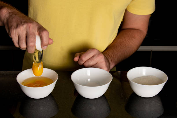 istock separating ingredients to make cake at home, detail cracking egg 1218804994