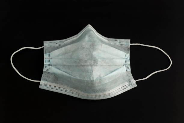 istock Disposable hygiene medical mask on a black background 1218807643