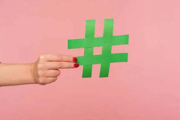 Photo of Blog marketing, social media trends. Closeup of female hand holding green hashtag sign, sharing tagged message