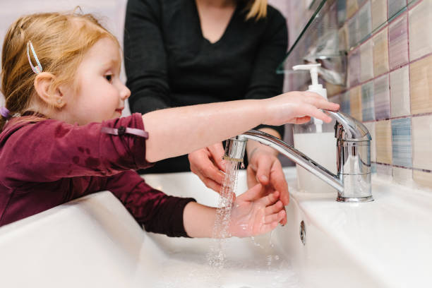 istock Washing hands. Stop spreading coronavirus. Preventive measures against Covid-19 infection. Mom tells child how to wash her hands with antibacterial soap properly, warm water rubbing nails and fingers. 1218809000