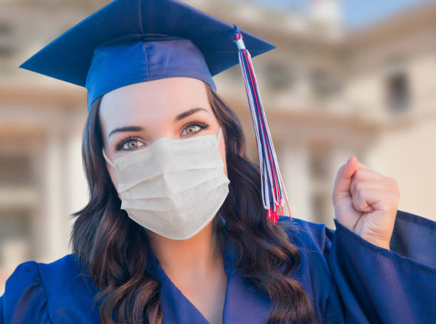 laureata in berretto e abito con maschera medica - graduation student women beauty foto e immagini stock