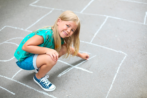Kid playing hopscotch on playground outdoors, children outdoor activities