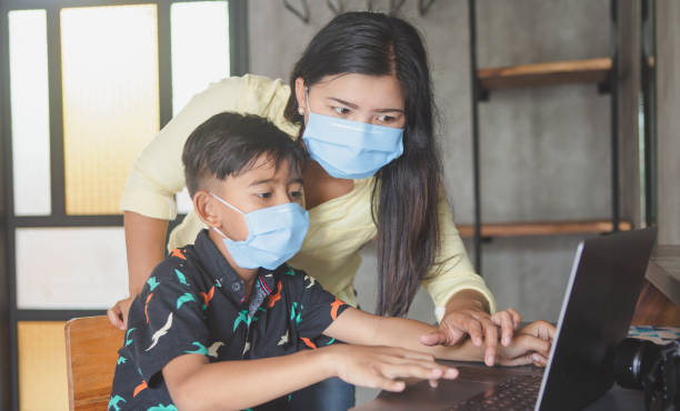 istock Lockdown and school closures. Mother helping her child with face mask studying online classes at home. Quarantine, self-isolation, online education concept, home schooler during COVID-19 pandemic 1218811680