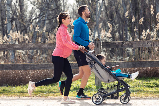 sportliches junges paar mit ihrem kleinen sohn läuft, während sie die gemeinsame zeit im freien genießen. - relaxation exercise child mother human pregnancy stock-fotos und bilder