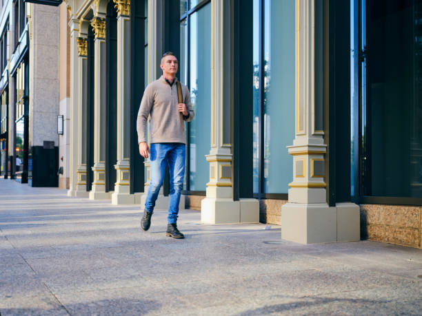 A young millennial man standing on a street in a modern urban area.